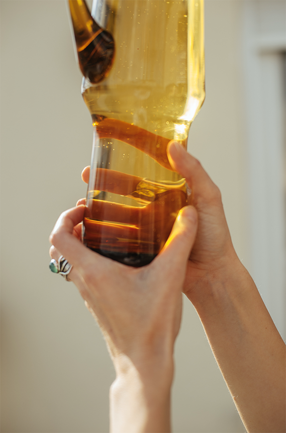 Hands holding an amber glass vessel.
