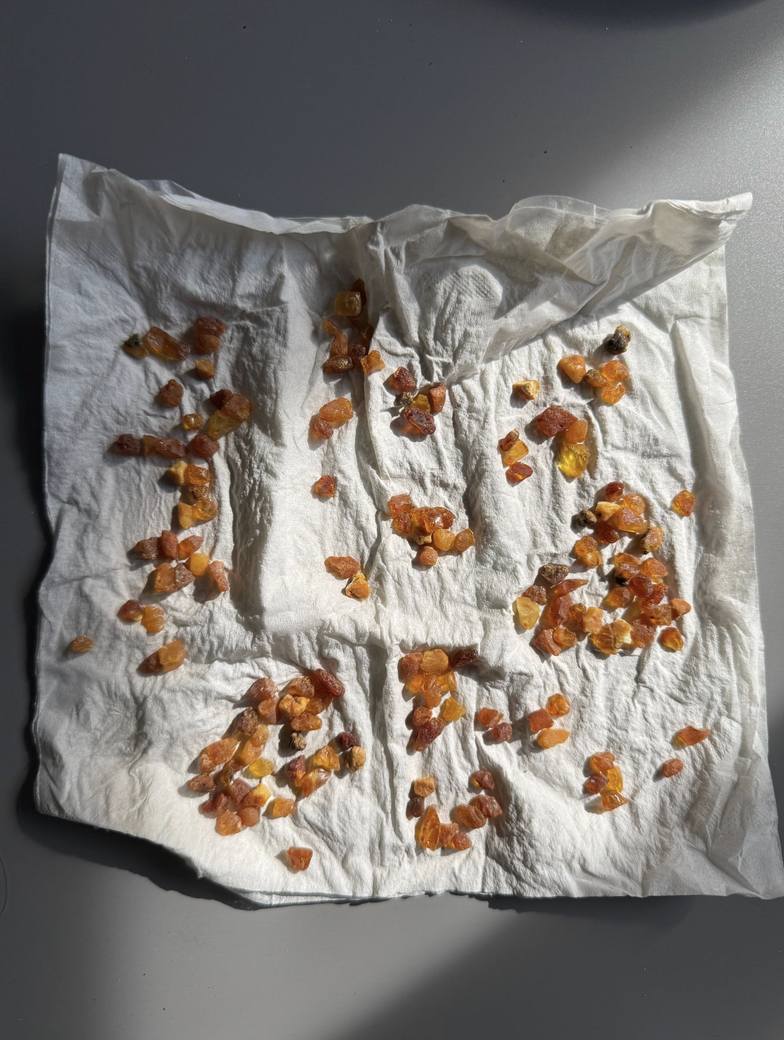 Raw amber stones laid out in patterns on white cloth in sunlight.